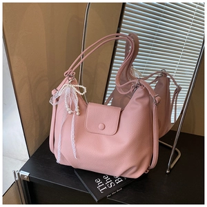 Detalle del bolso tote de cuero rosa con colgante de lazo de perlas y solapa magnética