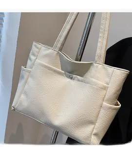 Detail of soft cream white tote bag featuring natural pleated texture and front pockets