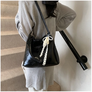 Sac cabas en cuir verni noir avec perles et nœud en dentelle sur les escaliers