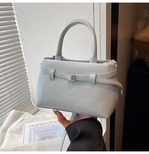 Detail of light blue pebble leather bucket bag with silver buckle and round handle