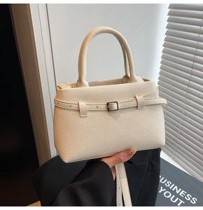 Detailed view of beige pebble grain leather texture on a trapezoid commute handbag