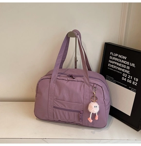 Detail of a purple canvas travel bag featuring front zipper pocket and cute plush charm