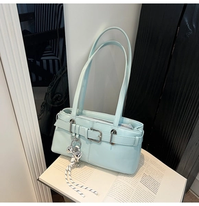 Dettaglio della borsa a spalla blu menta in ecopelle con fibbia e ciondolo a corda
