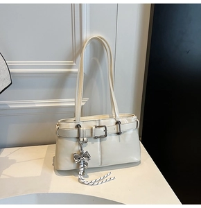 Dettaglio borsa crema in pelle con ciondolo a fiocco metallico e nappa in corda intrecciata
