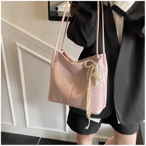 Détail du sac cabas rose en cuir verni avec breloque nœud perlé et texture plissée