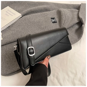 Close-up of black geometric leather crossbody bag with silver buckle and sleek modern texture