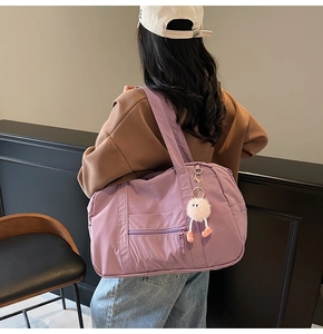 Detail view of large purple canvas travel bag with zip pockets and a pink plush charm