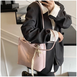 Détail d'un sac cabas rose en similicuir froissé avec breloques en perles et dentelle