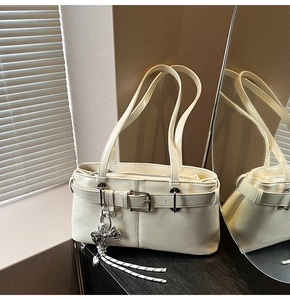 Dettaglio della borsa in pelle PU bianco crema con ciondolo a cuore e nappe in argento