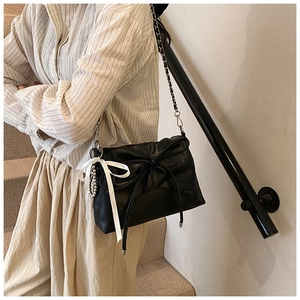 Detail of black bow shoulder bag featuring white silk ribbon and silver chain strap