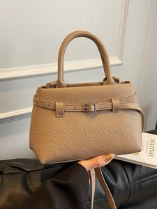 Beige faux leather bucket handbag with decorative buckle and adjustable shoulder strap