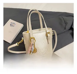 Close-up of cream white bucket bag with pearl texture finish and golden hardware