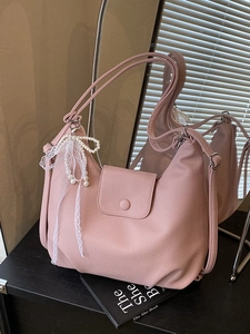 Bolso tote grande rosa de cuero sintético con lazo de encaje y perla frente al espejo