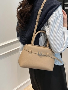 Beige lychee pattern bucket bag with silver buckle strap shown in a lifestyle scene