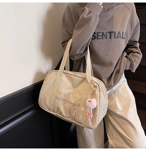 Detail view of large beige canvas tote bag with side zipper pocket and cute pink plush charm