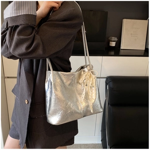 Détail du sac seau métallisé argenté avec nœud en dentelle et breloque en perles