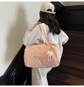 Woman carrying a large pink canvas travel bag on stairs featuring a cute plush pendant