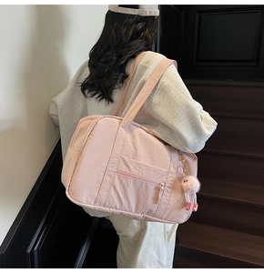 Detailed side view of a large pink canvas travel bag carried by a model on stairs