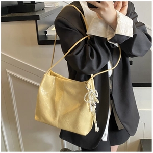 Détail d'un sac à bandoulière jaune clair en cuir froissé avec breloque nœud en perles