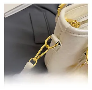 Close-up of premium gold-toned metal hook and D-ring on ivory bucket handbag
