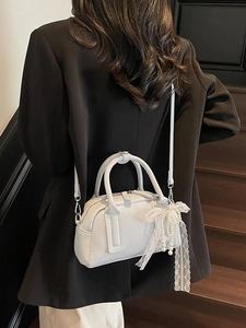 Chic beige leather bowling bag with pearl charm and shoulder strap on a model