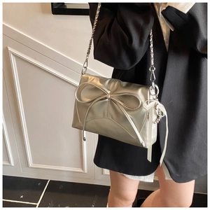 Detail of silver metallic bow square bag with chain strap and silk ribbon charm