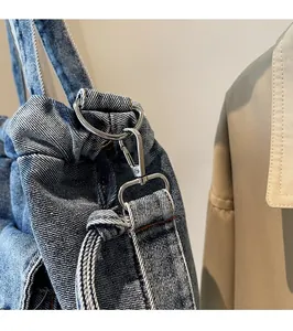 Detailaufnahme des silbernen Metallhakens und D-Rings an der blauen Denim-Umhängetasche