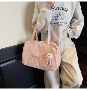 Pink waterproof nylon tote bag with multiple pockets and a plush monster charm detail