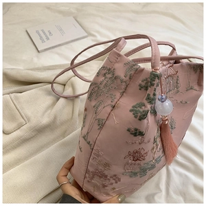 Dettaglio della borsa a secchiello in seta rosa con ricami cinesi e nappa decorativa