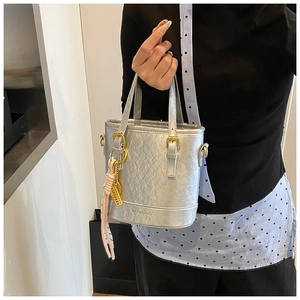 Close-up of silver bucket bag featuring textured metallic finish and pink tassel detail