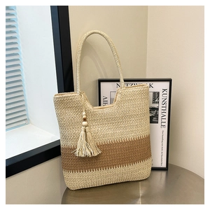 Close-up of woven straw tote bag with color blocking design and tassel bead detail