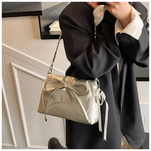 Detail view of a silver metallic bow shoulder bag with chain strap and pearl charm