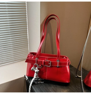 Dettaglio di borsa a spalla rossa con ciondolo a fiocco argento e fibbia decorativa