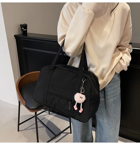 Detail of black large capacity canvas travel bag with a decorative pink plush charm
