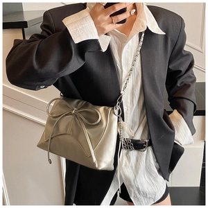 Chic silver crossbody bag with large bow detail and metal chain strap on model