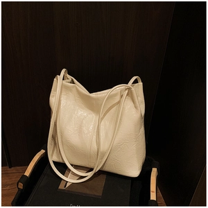 Détail d'un grand cabas en cuir crème à texture plissée dans un panier en bois rustique