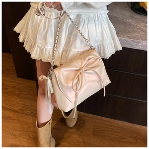 Detail of off-white satin shoulder bag with oversized bow and silver chain strap