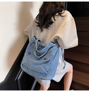 Detalle del bolso tote de mezclilla lavada con dos bolsillos frontales y botones negros