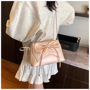 Detail shot of the large 3D bow and elegant metal chain strap on the light pink square bag