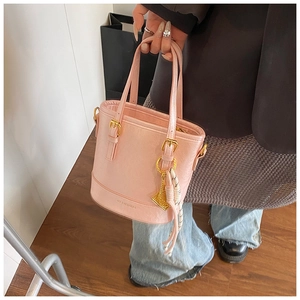 Detailed close-up of pink bucket bag with gold hardware and stylish tassel charm