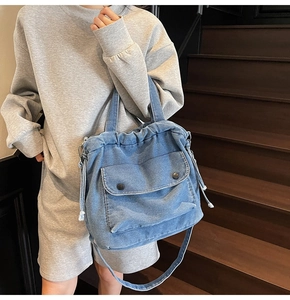 Detailansicht der blauen Denim-Umhängetasche mit Kordelzug und vorderer Klappentasche