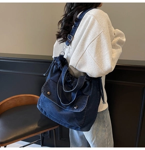 Detalle del bolso de tela vaquera azul oscuro con correa ajustable y bolsillos con hebilla