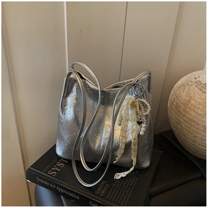 Détail d'un sac à bandoulière argenté plissé avec pendentif en perles et dentelle