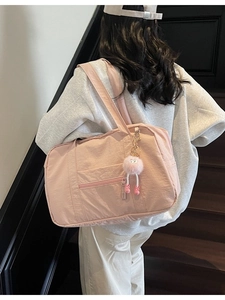 Pink nylon canvas tote bag with pompom shown from back on model for scale