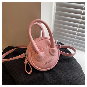 Detail of pink round handbag with lychee texture leather and heart-shaped handle link