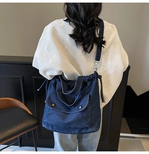 Detalle de un bolso tote de tela vaquera azul oscuro con cordón y bolsillos con botones