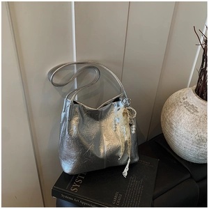 Détail du sac à bandoulière plissé argenté avec un élégant pendentif en perles et dentelle