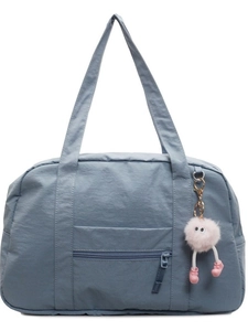 Large blue canvas travel bag with top handles and a cute pink plush monster charm