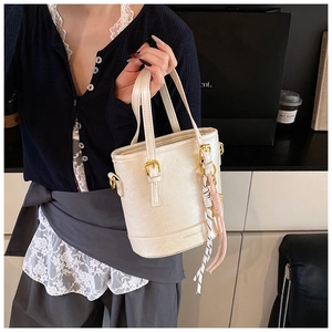 Close-up of minimalist cream bucket bag featuring fine leather texture and metal buckle