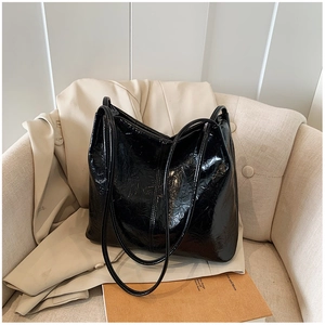 Détail de la texture en cuir verni noir plissé sur ce grand sac cabas élégant